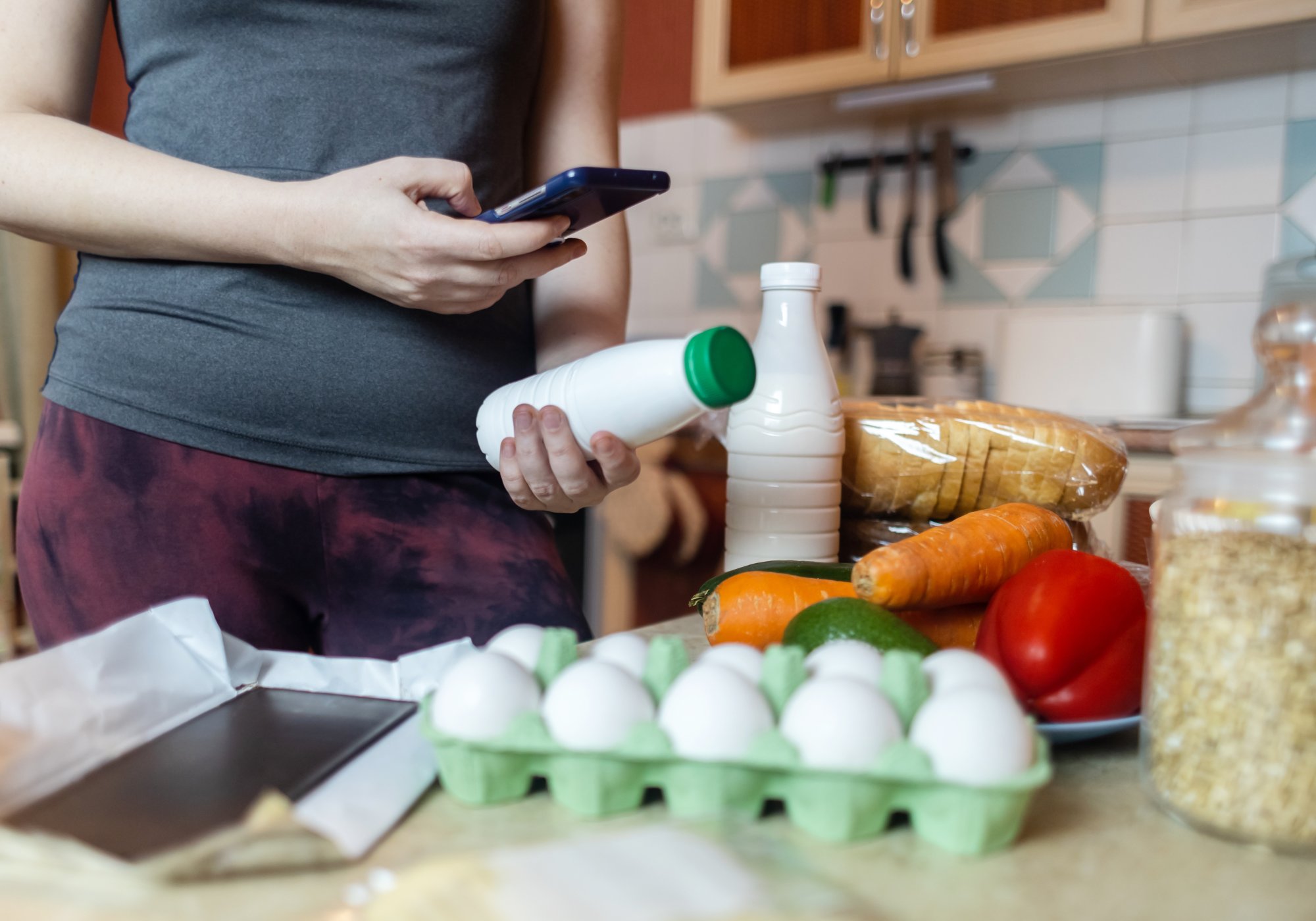 Woman logging groceries on her phone to track protein and macros as part of a metabolic reset in Katonah, NY